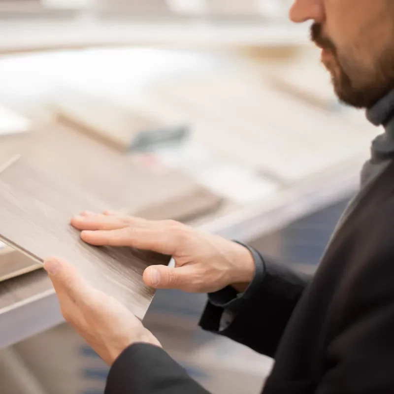 Services-Intro Customer browsing the retail flooring showroom, holding a sample | Pilot Floor Covering